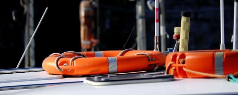 Two orange lifebuoys on a sailboat as part of the boats safety equipment. 